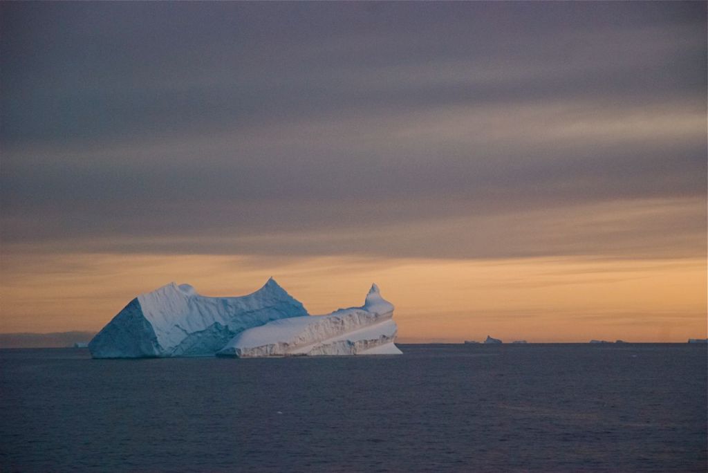 Sunlit icebergs gleam on the horizon in the Antarctic Sound.